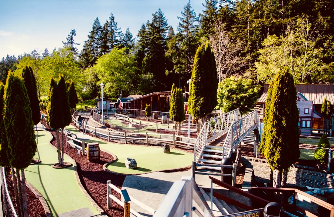 Landscaped mini golf fairways lined with cypress trees at Station 49